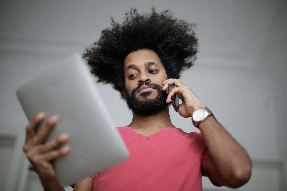 Small business owner checking a tablet while taking a customer call, the office work field service software pricing needs to justify