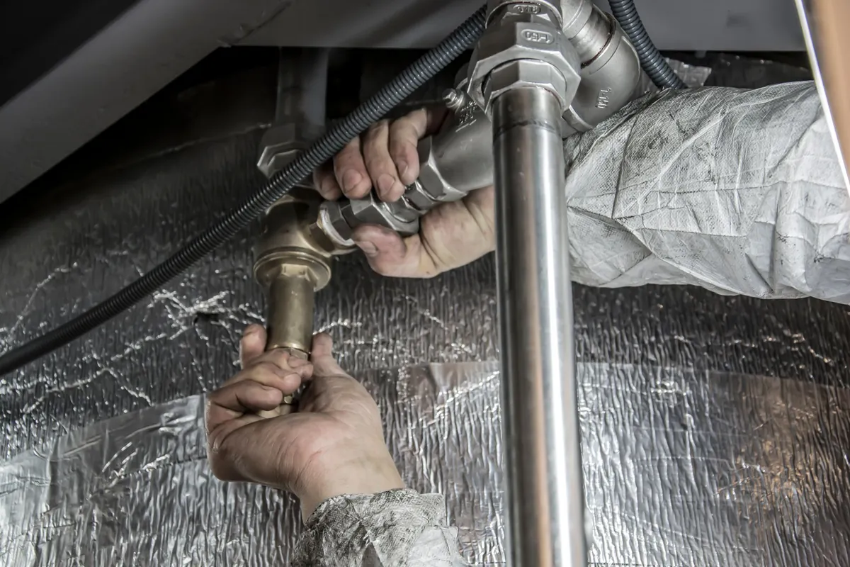 Close view of a plumber's hands installing steel pipe fittings indoors, skilled plumbing work that good scheduling software keeps on track