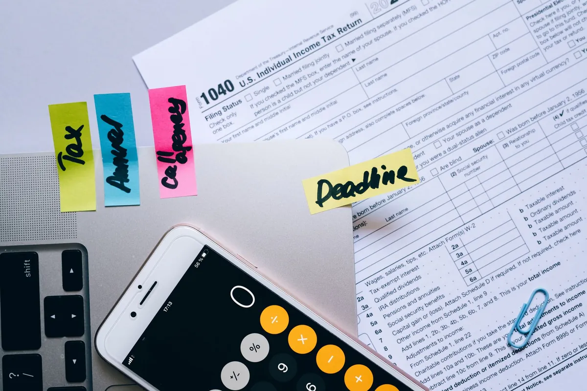 Smartphone showing a calculator app lying on invoices and paperwork on a desk, working out the real cost of field service software
